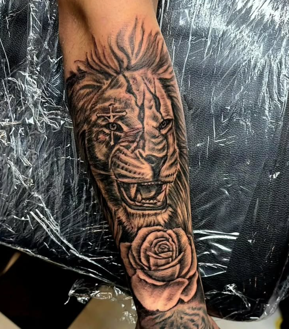 Realistiskt lejon med ros i black and grey på underarm