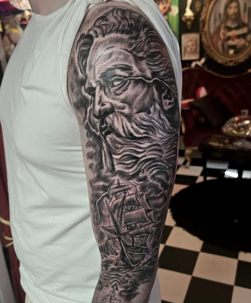 Black and grey överarmstatuering med Poseidon och segelfartyg